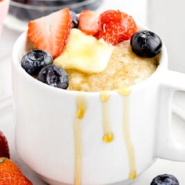 A white cup with a pancake in a mug in it.