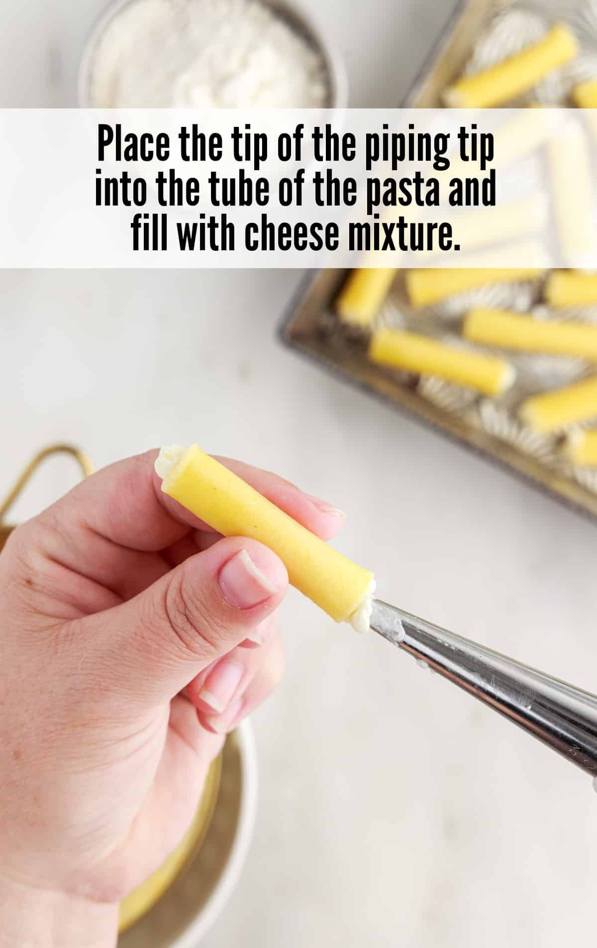 placing the tip of the piping tip into the tube of the pasta and filling with cheese mixture