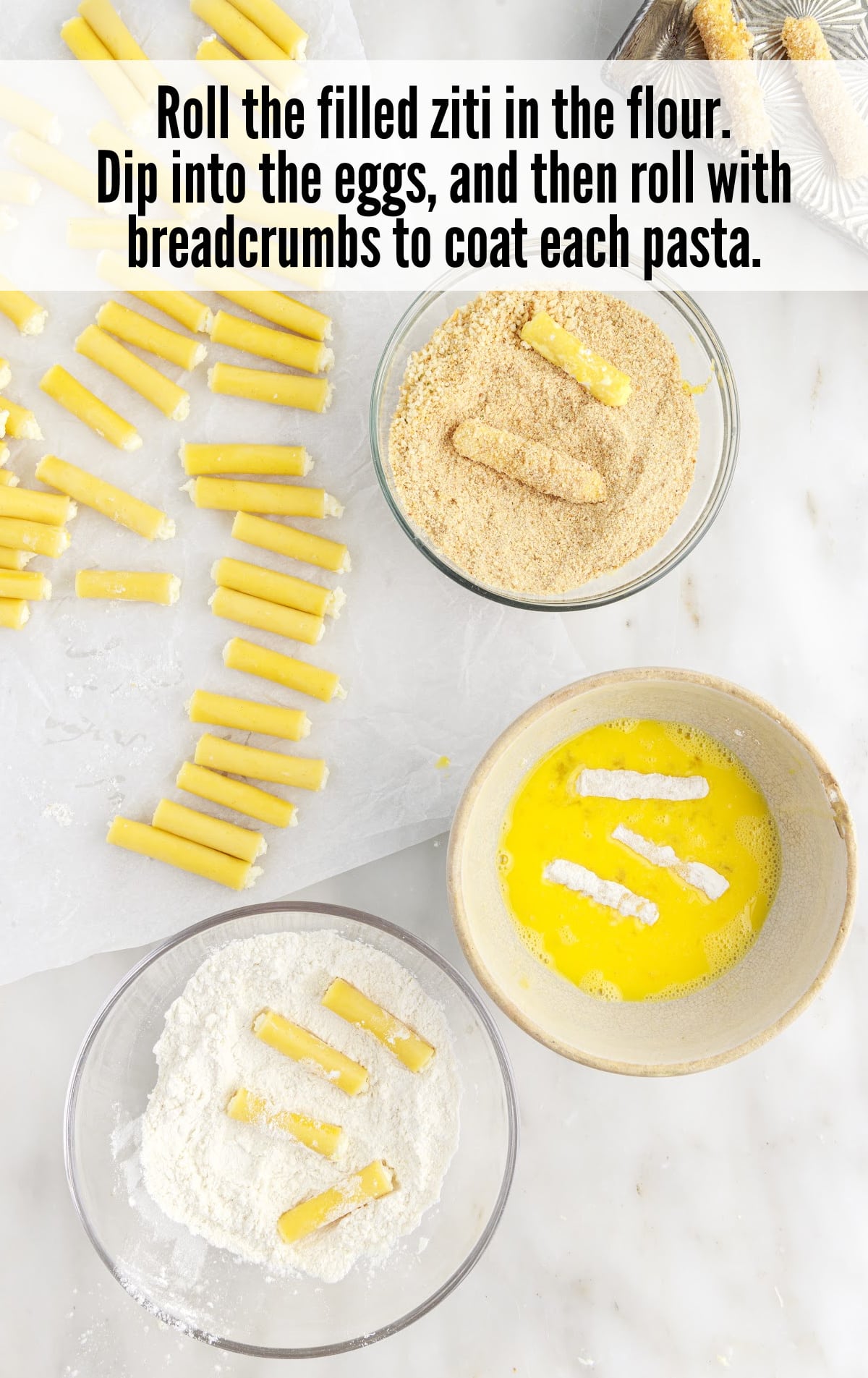 rolling the filled ziti in the flour, dipping into the eggs and then rolling with breadcrumbs to coat each pasta.