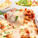 A fork is lifting a cheesy bite of baked ritagoni.
