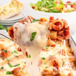 A fork is lifting a cheesy bite of baked ritagoni.