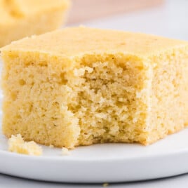 a piece of Cornbread on a plate with a bite on it