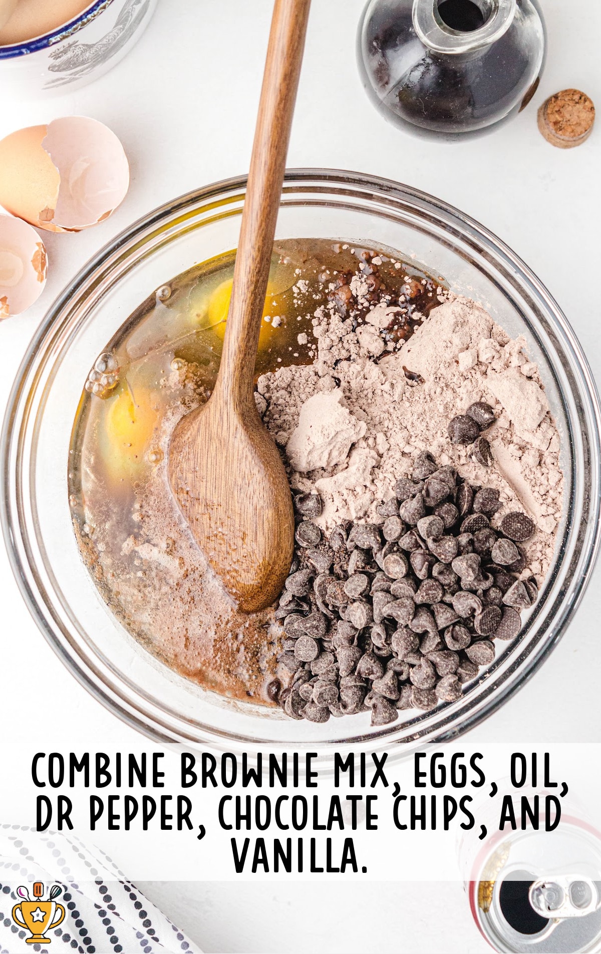 brownie mix, eggs, oil, dr pepper, chocolate chips and vanilla added and mixed in a bowl with a wooden spoon