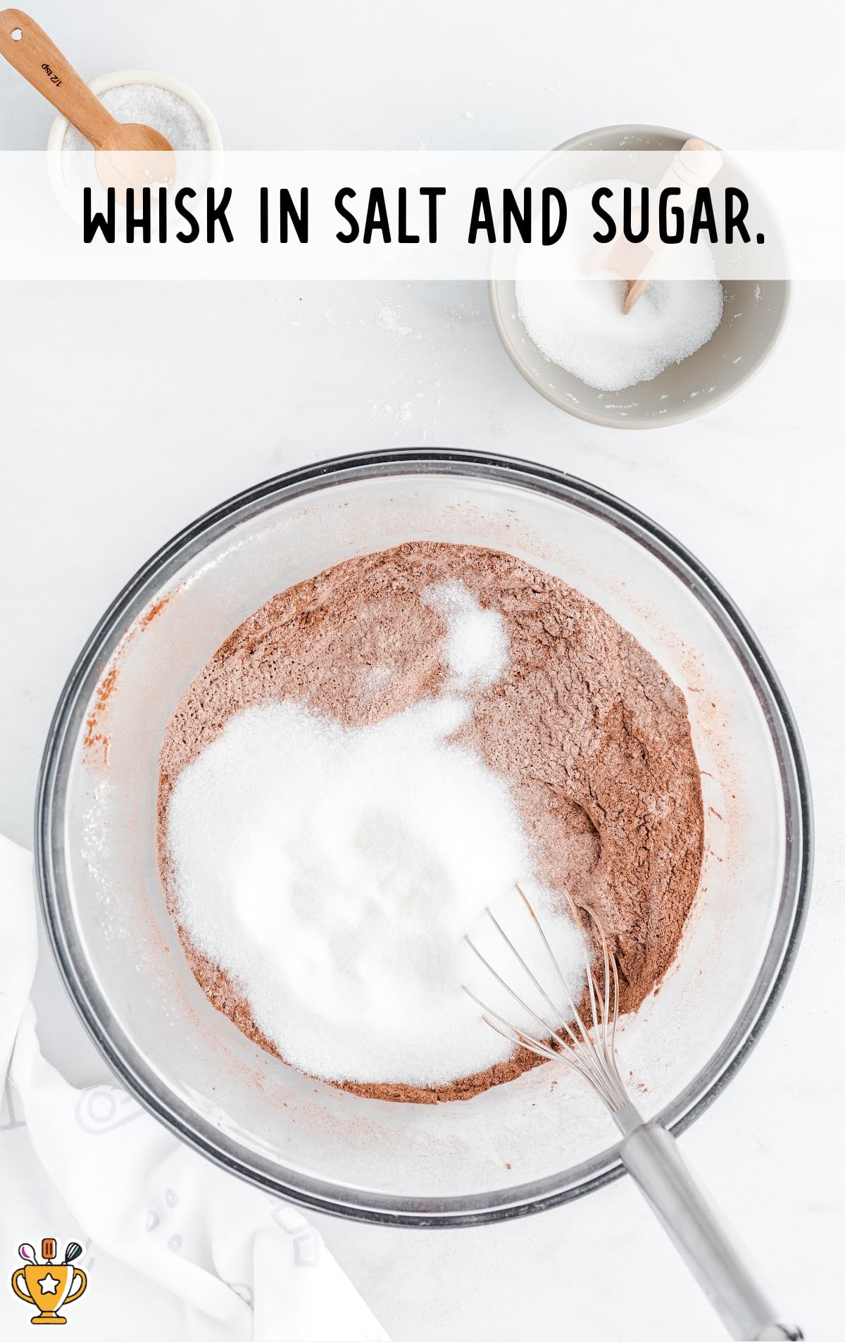 salt and sugar added with other ingredients for making Hershey Chocolate Cake in a clear glass bowl