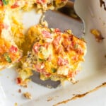 a spatula holding a piece of Sausage Breakfast Casserole in a baking dish