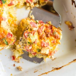 a spatula holding a piece of Sausage Breakfast Casserole in a baking dish