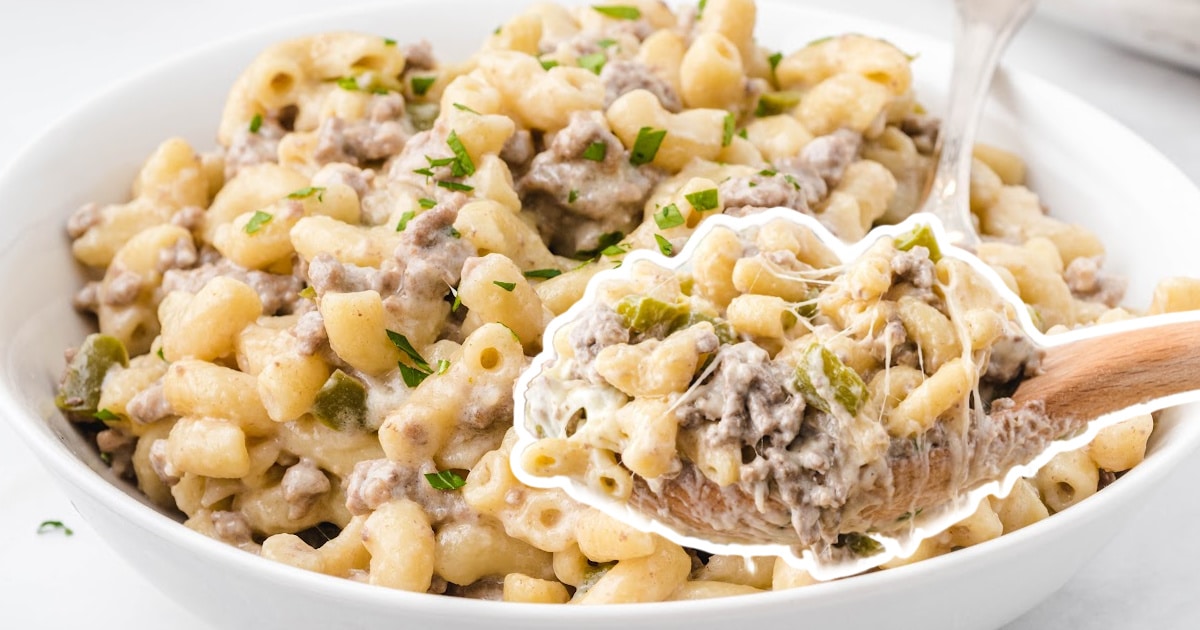Philly Cheesesteak Pasta in a bowl with a spoon and a wooden spoon