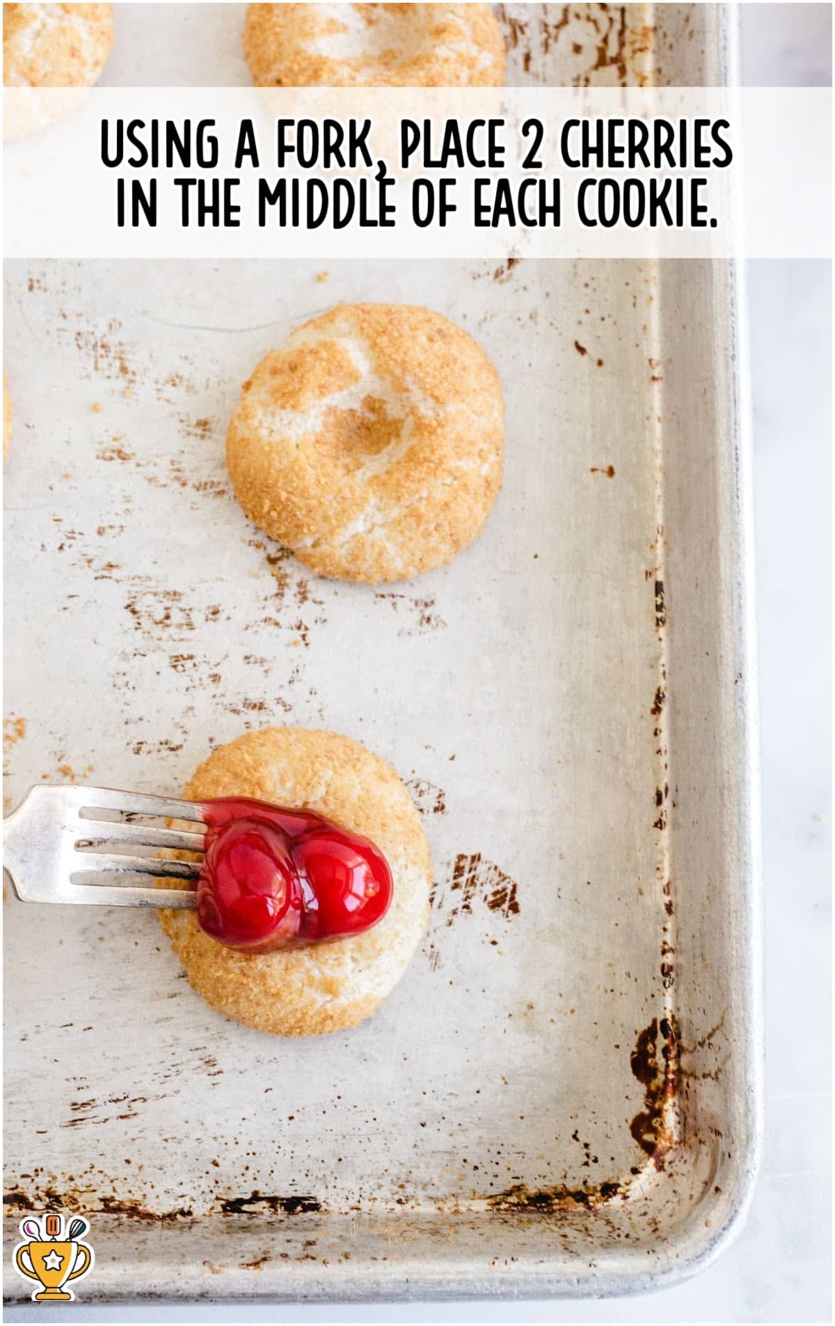 placing 2 cherries in the middle of each cookie using a fork