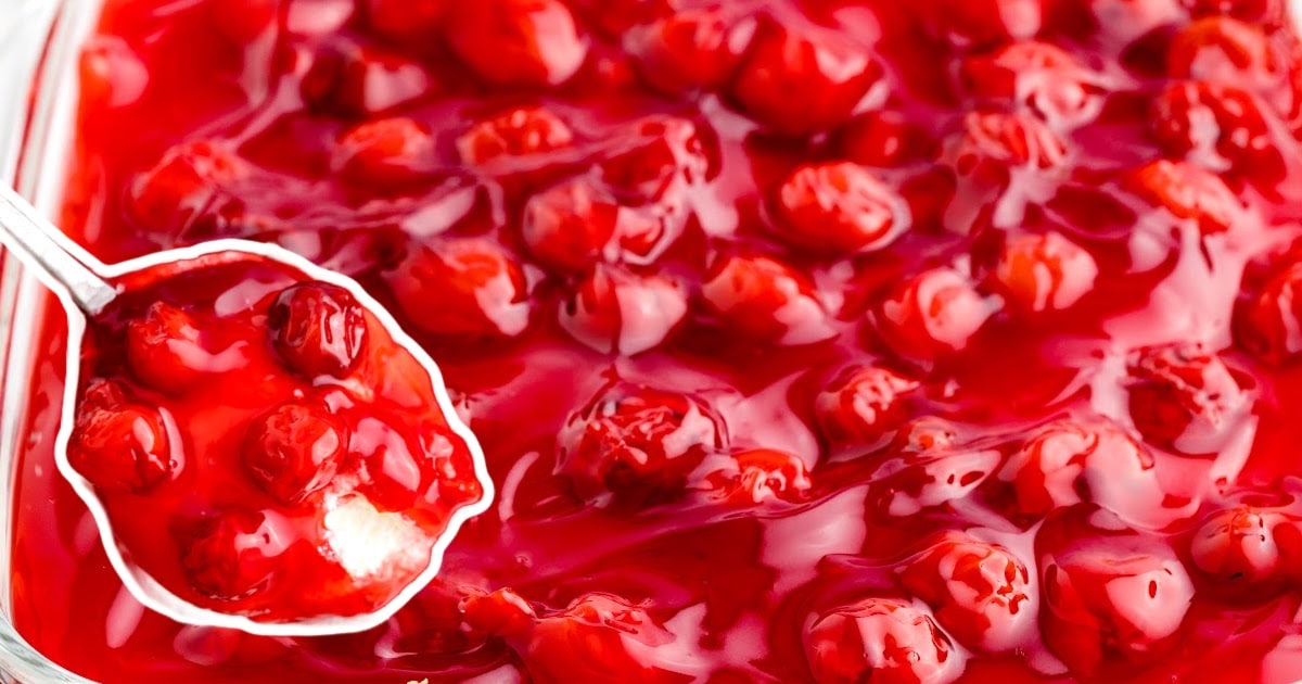 a spoon holding some Cherry Cheesecake Dip and some more in a baking dish