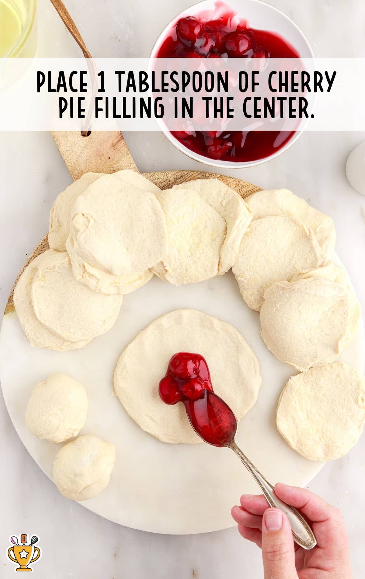 a hand holding a spoon with cherry pie filling