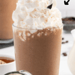 Creamy coffee smoothie topped with whipped cream and a striped straw, shown with banana and cocoa ingredients.