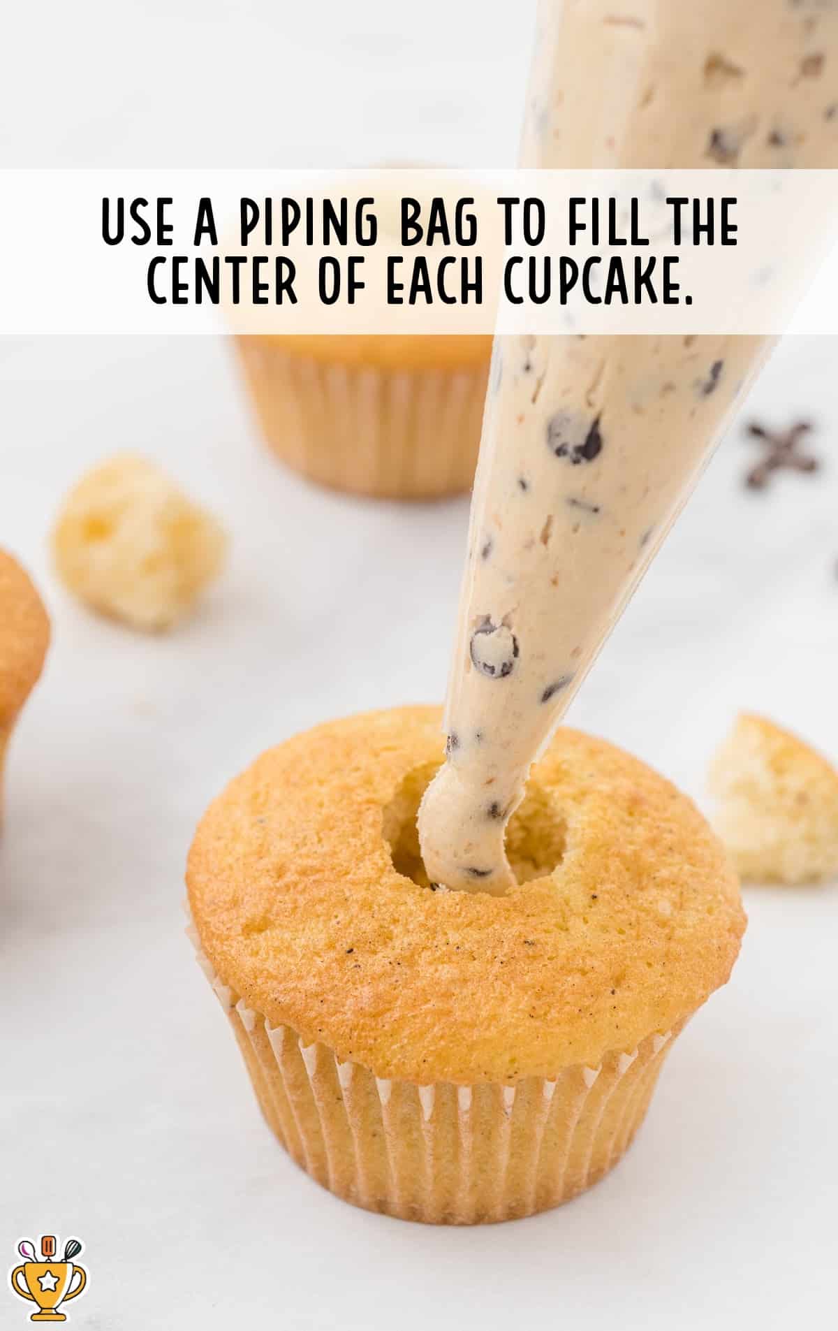 using a piping bag to fill the center of a cupcake