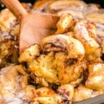 cinnamon roll casserole in a crockpot with a wooden spoon in it