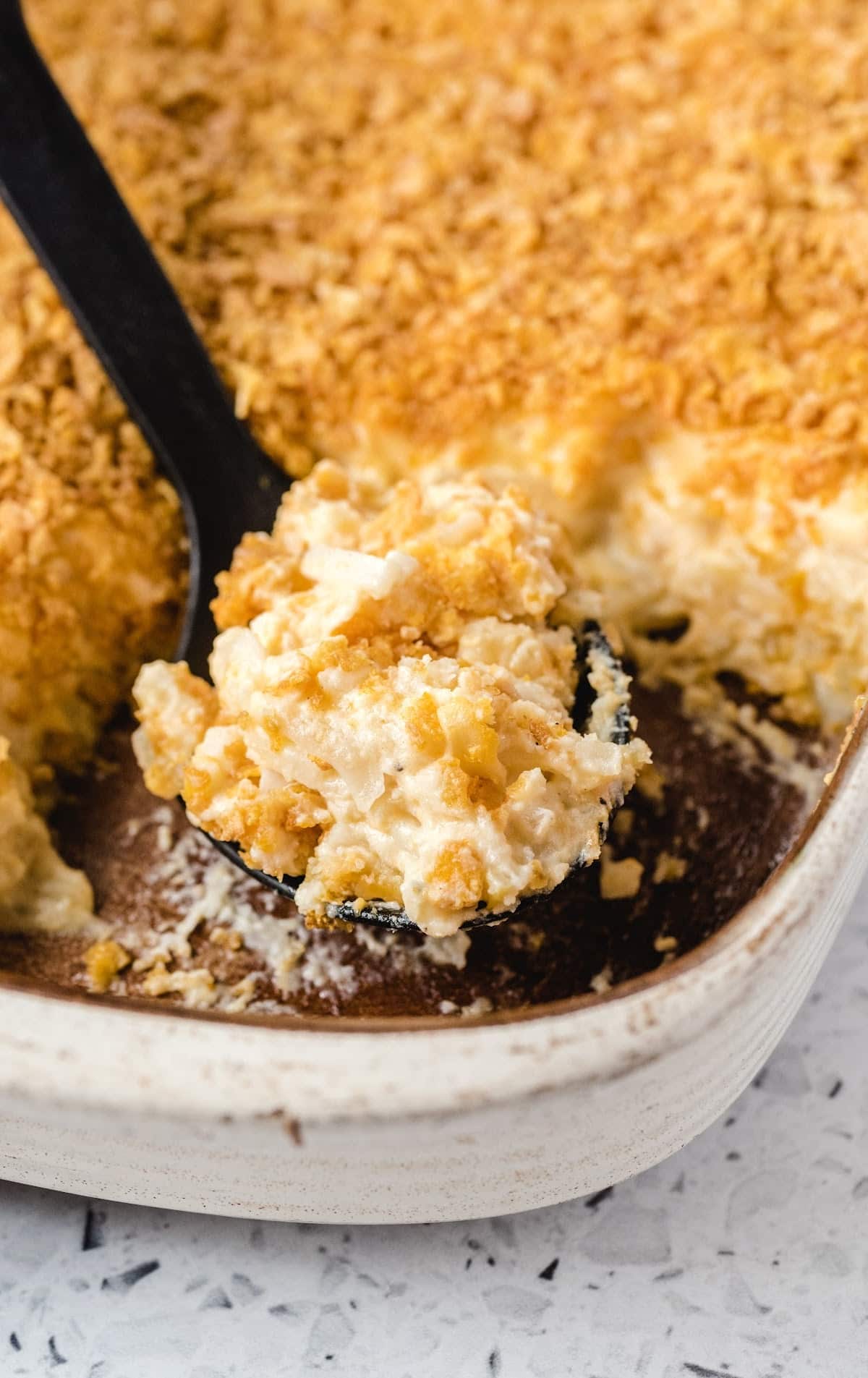 Funeral Potatoes in a baking tin and some on a spoon
