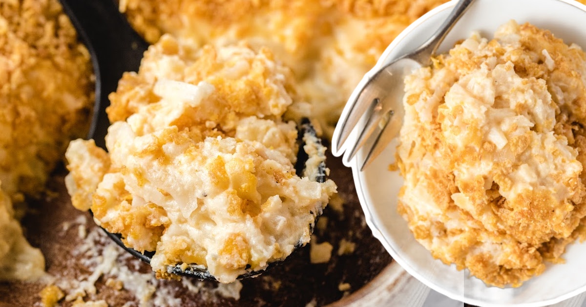 a black spoon holding some Funeral Potatoes and some on a white plate with a fork