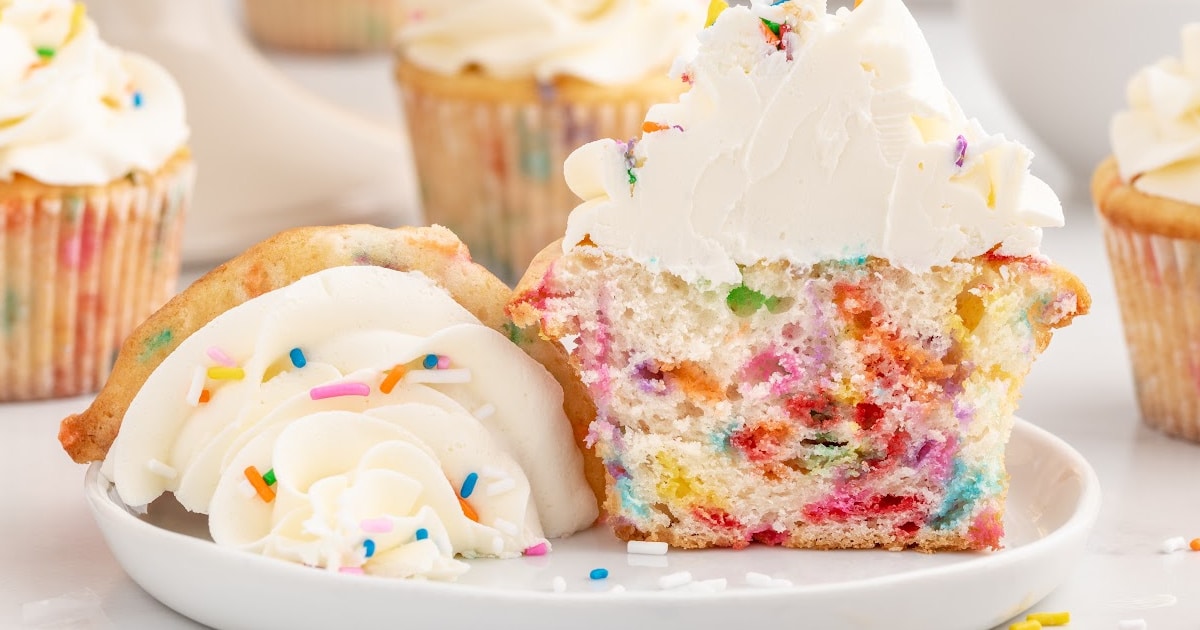 A cut open Funfetti Cupcake on a white plate.