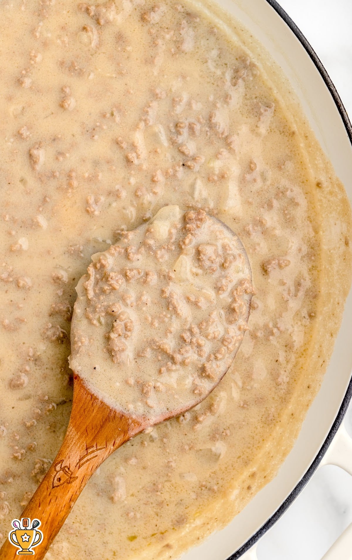 Hamburger Gravy in a skillet with a wooden spoon