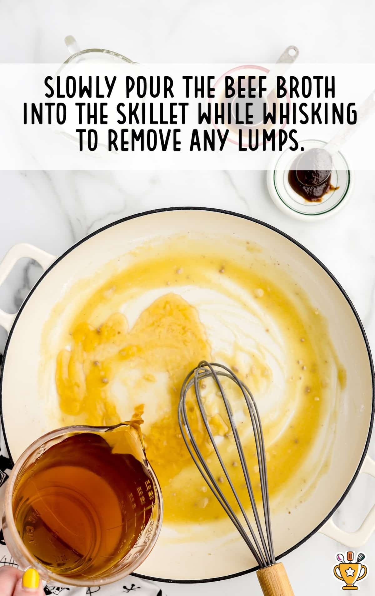 pouring beef broth into the skillet while whisking with a whisker