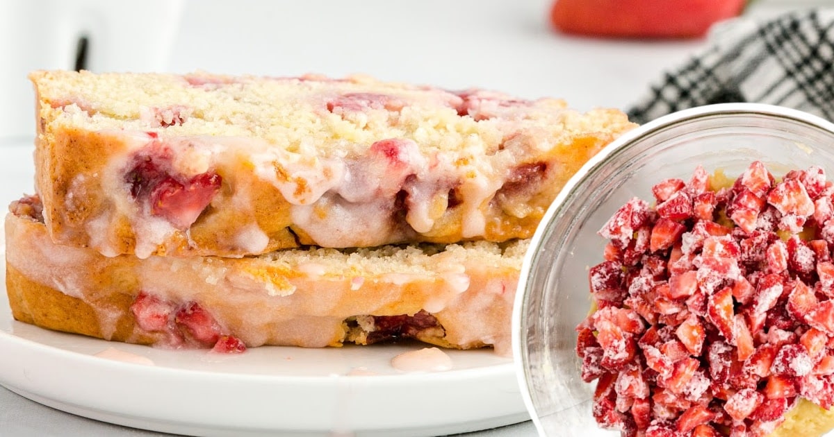 two pieces of Strawberry Bread on a white plate and some strawberry slices in a bowl