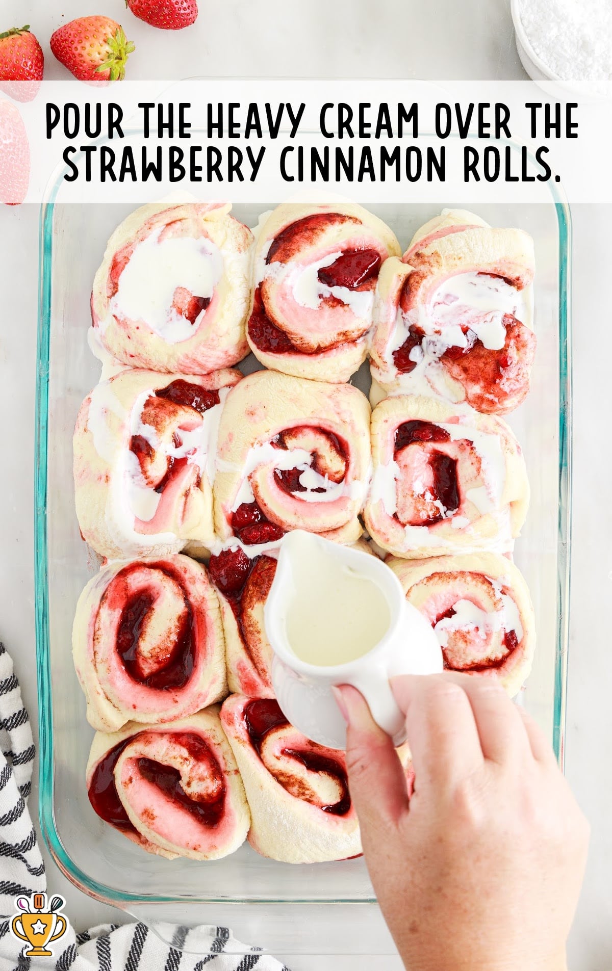 pouring heavy cream over the strawberry cinnamon rolls