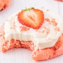a Strawberry Cookie with Cream Cheese Frosting with a bite on it and slice of strawberry on top