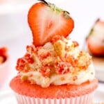 a Strawberry Crunch Cupcake on a plate with a strawberry on top