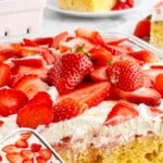 Strawberry Tres Leches Cake in a glass baking dish, featuring a moist yellow sponge soaked in three milks, topped with whipped cream and a generous layer of fresh sliced strawberries, with a cut slice shown on a plate in the background.