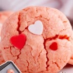 Valentine Cookie on a plate next to a baking tray full of cookies.