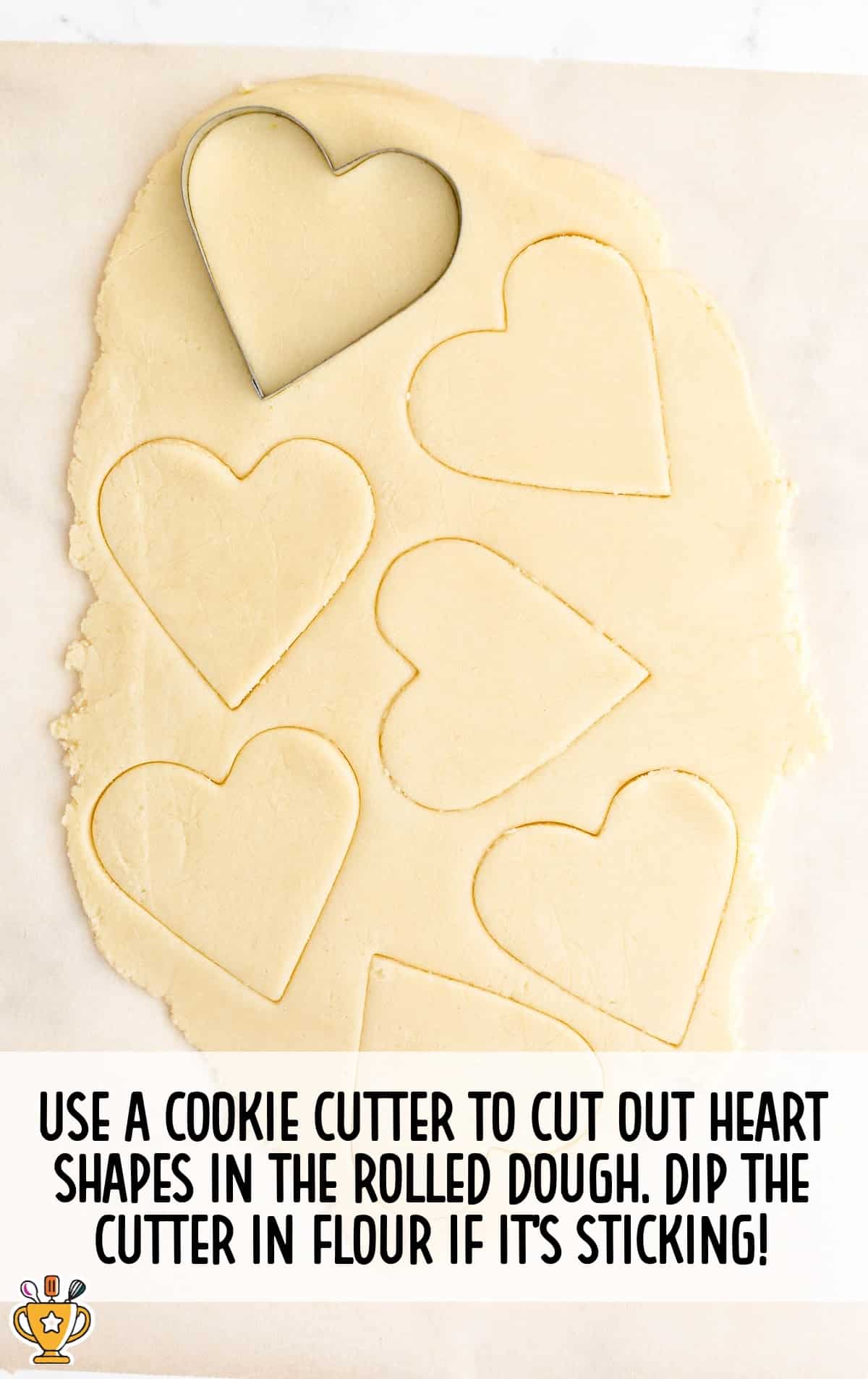 cookie cutter cutting out heart shapes in the rolled dough