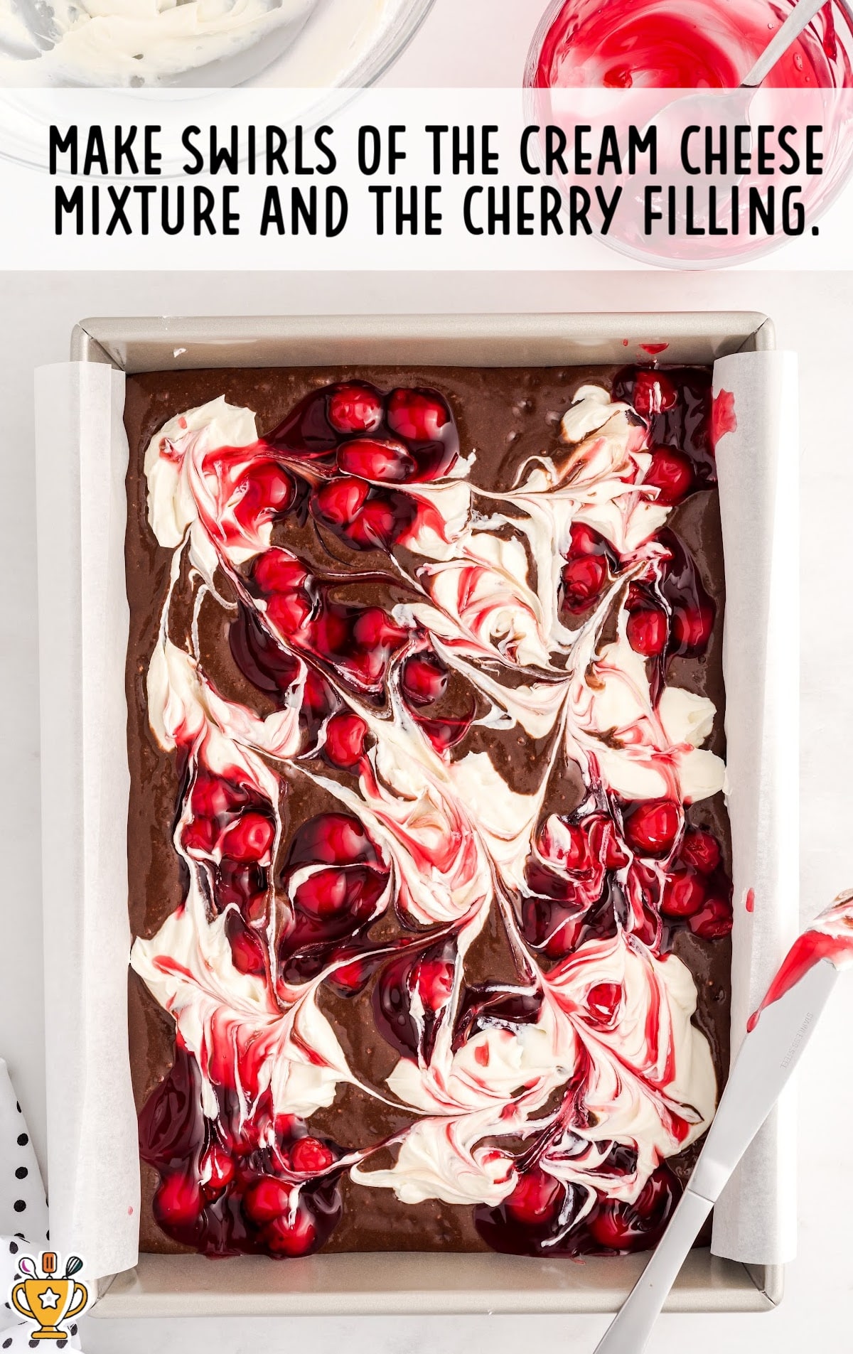 The brownie batter, cherries, and cheesecake mixture is swirled together.