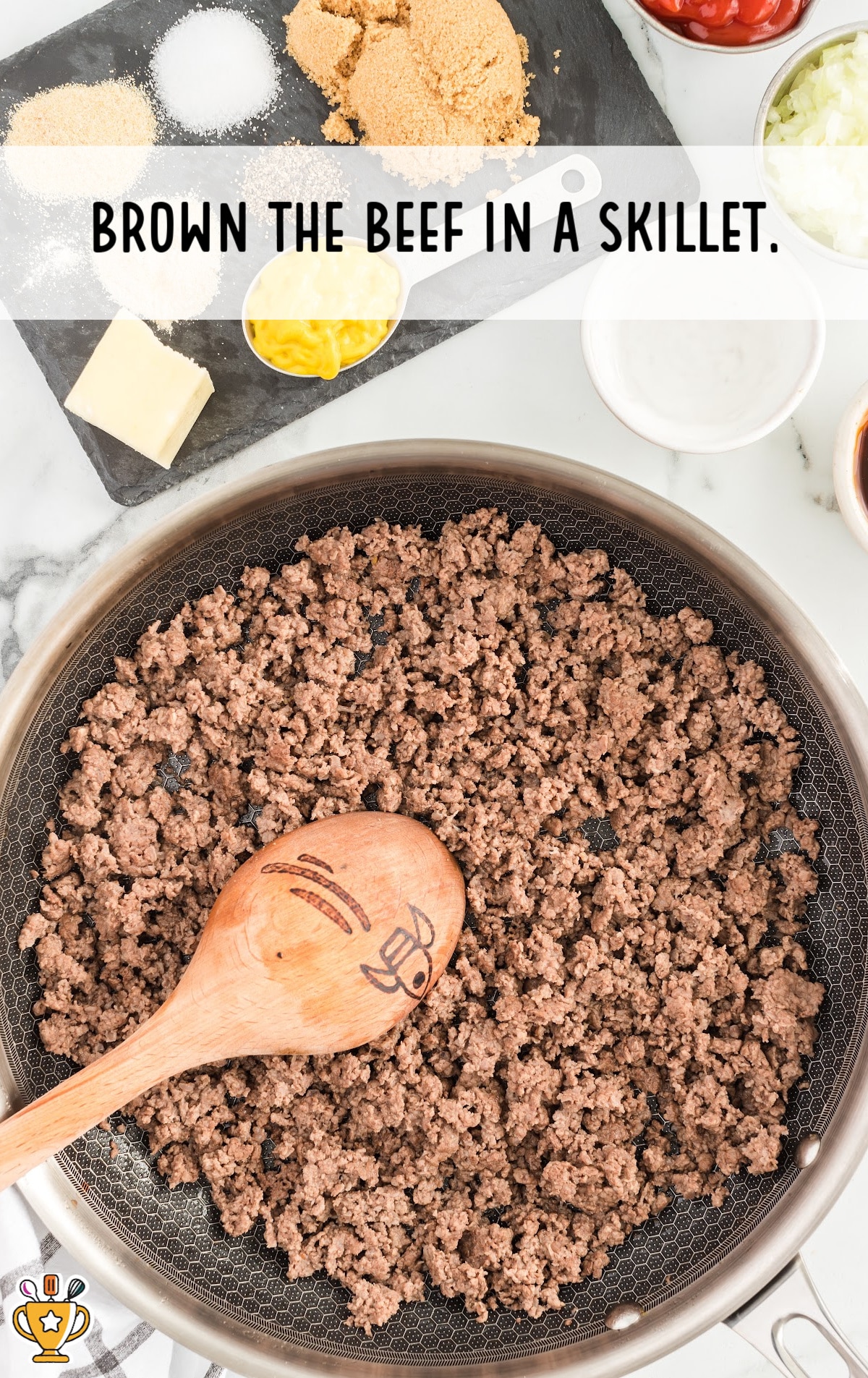 brown beef in a skillet with a wooden spoon in the skillet