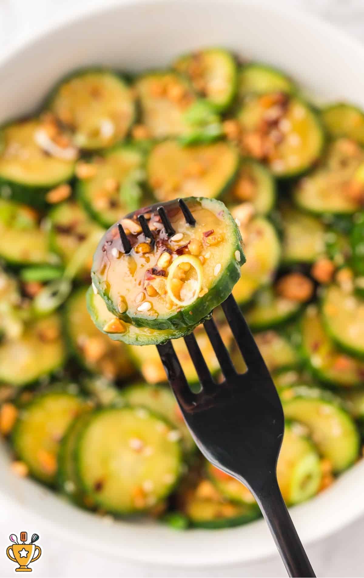 a fork holding some Asian Cucumber Salad and a some more in a bowl
