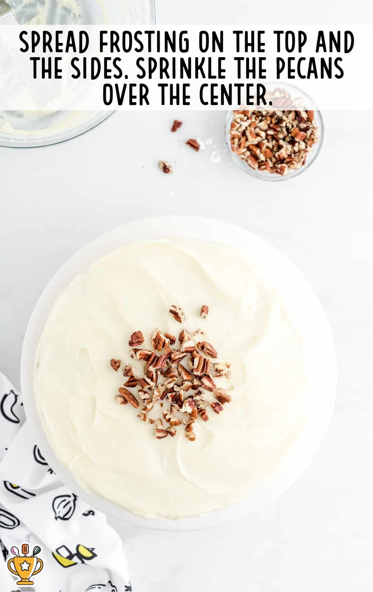 frosting spread on the top and pecans sprinkled over the center