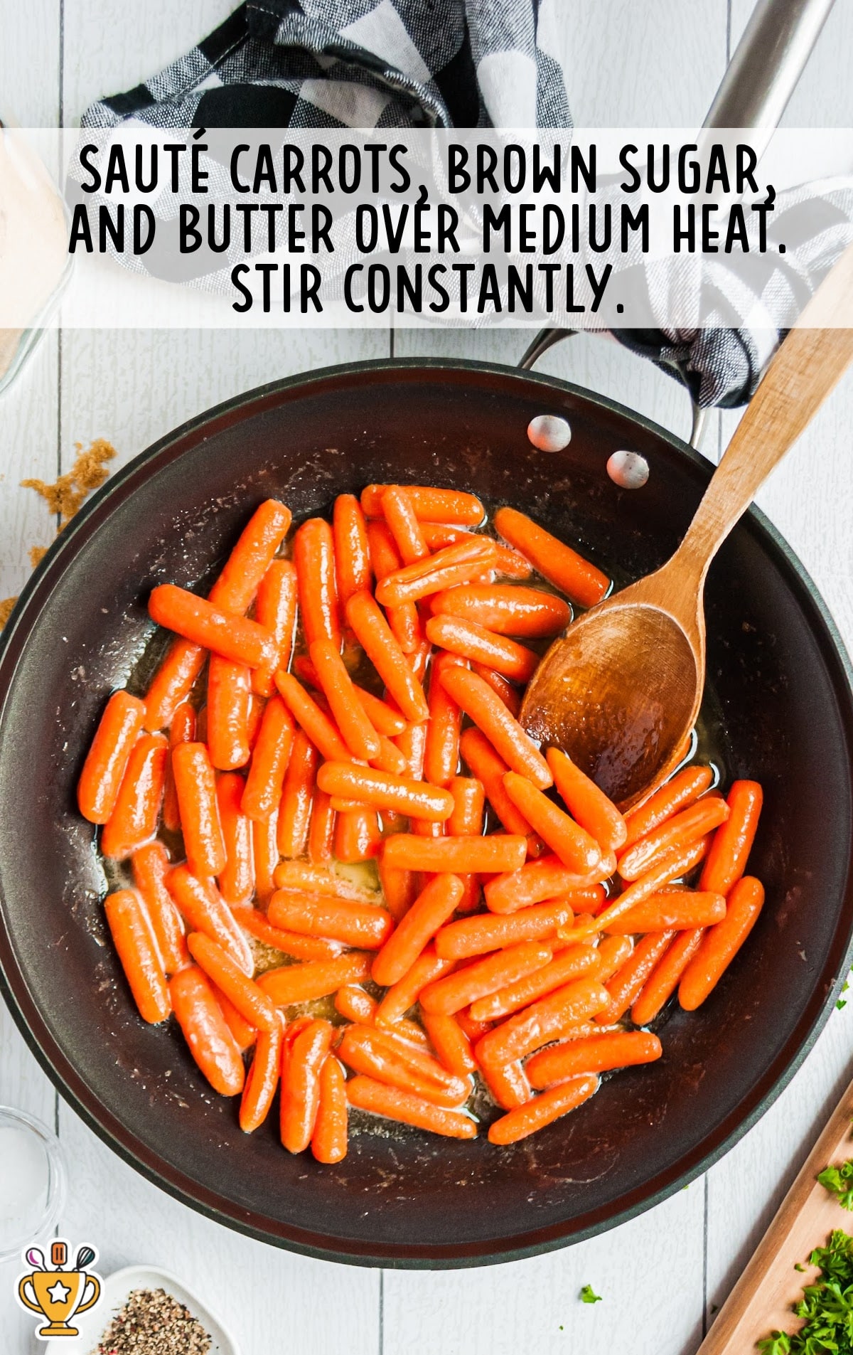 Glazed Carrots in a frying pan with a wooden spoon in it