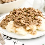 A plate of mashed potatoes covered in hamburger gravy.