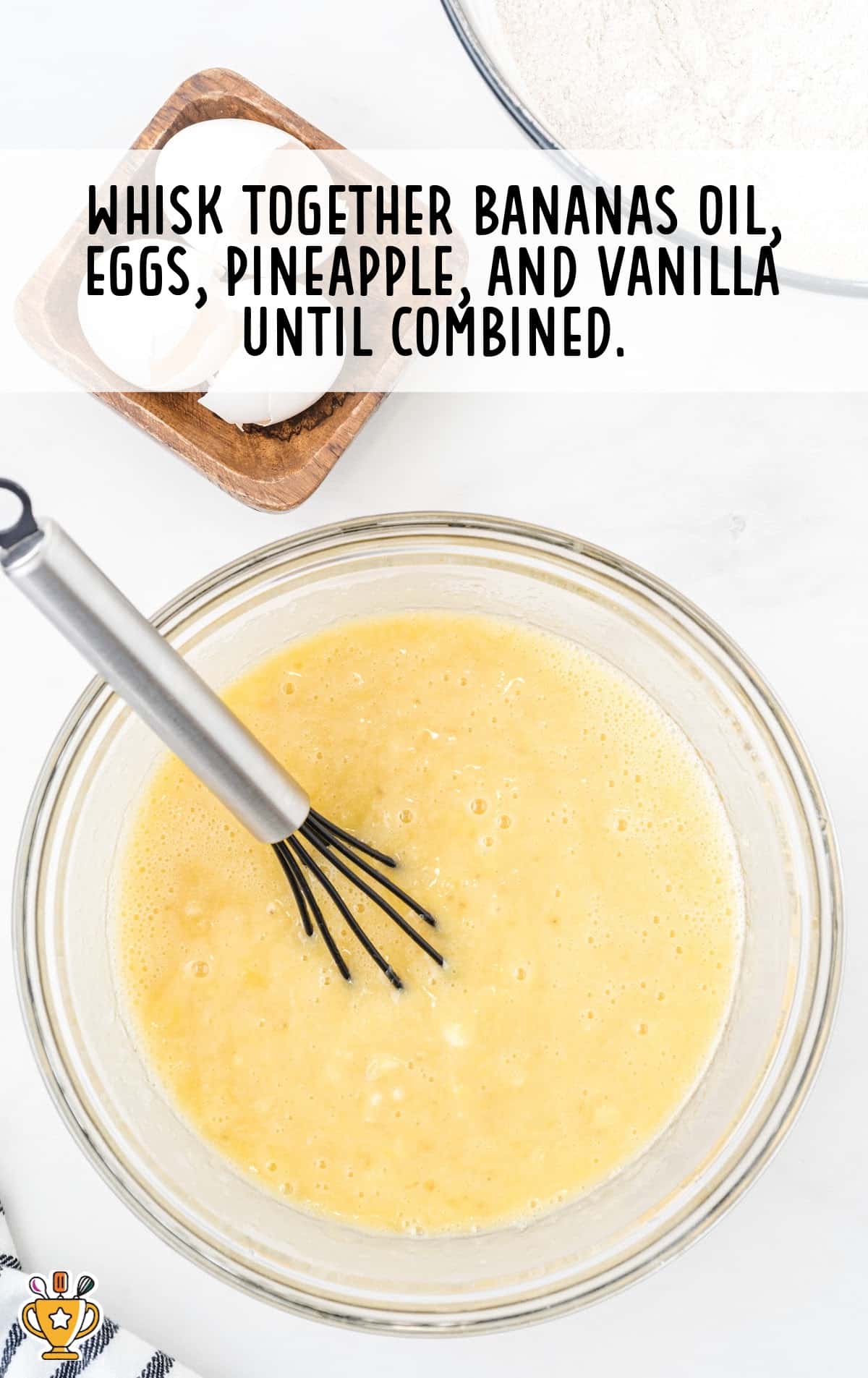 bananas oil, eggs, pineapple and vanilla added in a bowl with a whisker