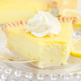 A piece of lemon custard pie with a bite out of it, and some whipped cream on top.