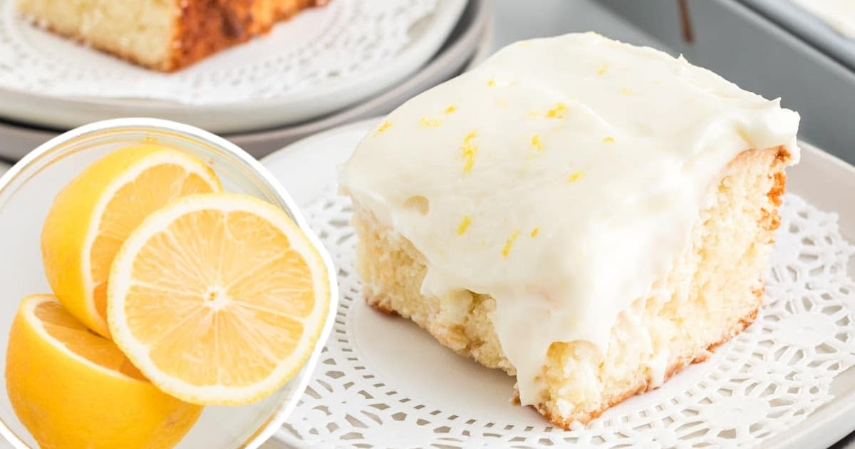 a piece of Lemon Sour Cream Cake on a plate and three lemon pieces on a plate