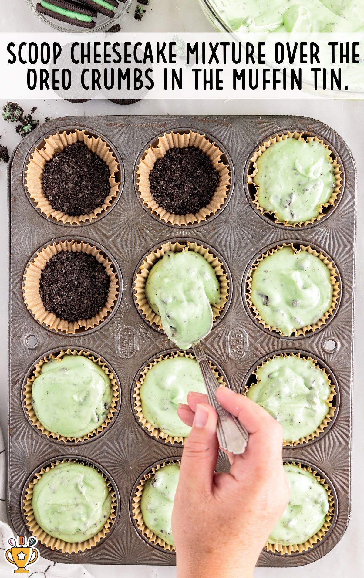 scooping cheesecake mixture over the oreo crumbs in the muffin tin