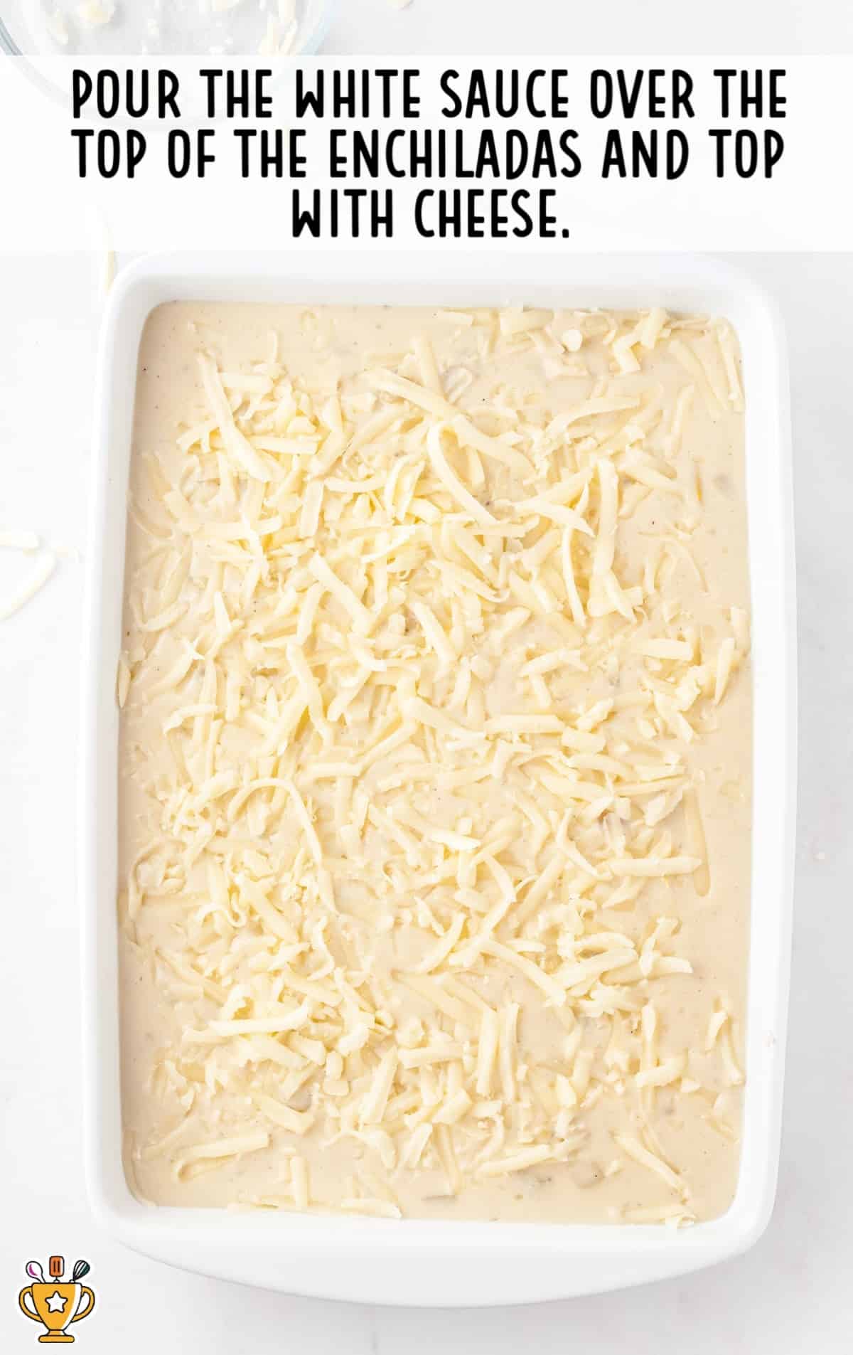 white sauce over the top of the enchiladas in a baking dish