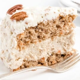 a piece of Carrot Cake Cheesecake on a plate with a fork