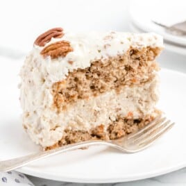 a piece of Carrot Cake Cheesecake on a plate with a fork