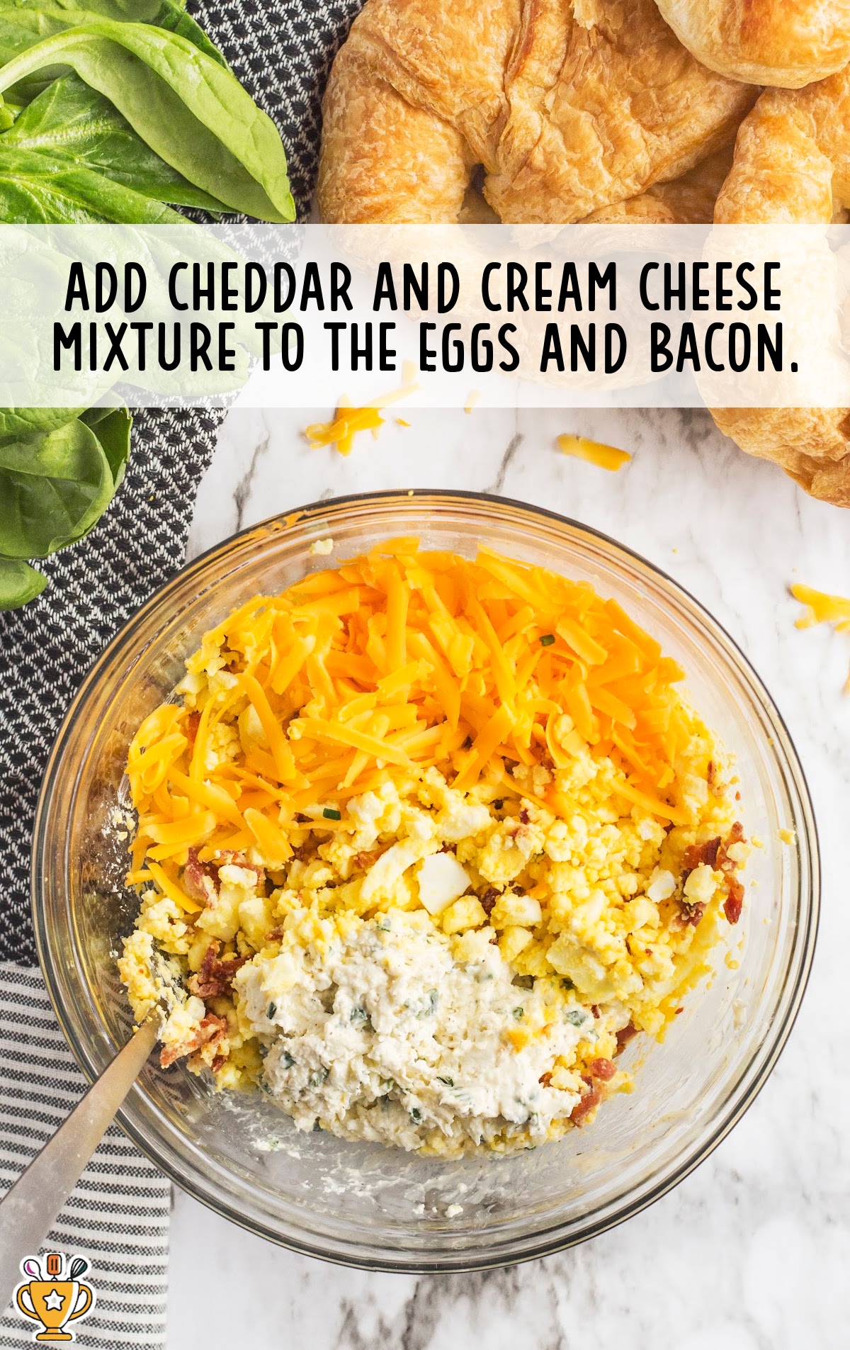cheddar and cream cheese mixture added in a bowl of eggs and bacon