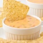 dipping a chip in a small bowl of Cheese Dip