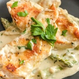 a black plate served with Creamy Chicken and Asparagus
