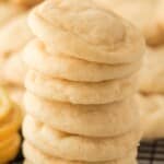 Stack of soft and chewy Lemon Sugar Cookies with a light, crinkled texture, displayed on a black wire cooling rack with more cookies and fresh lemons blurred in the background. Stack of soft and chewy Lemon Sugar Cookies with a light, crinkled texture, displayed on a black wire cooling rack with more cookies and fresh lemons blurred in the background.