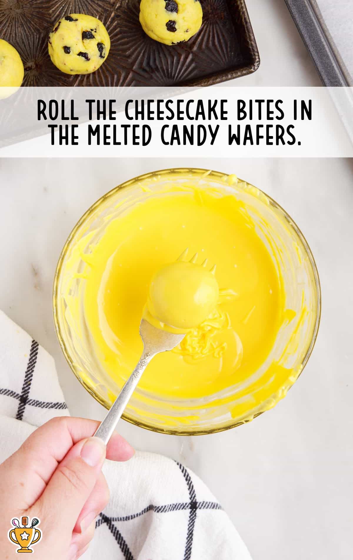 a fork holding a cheesecake bite after rolling it in the melted candy wafers