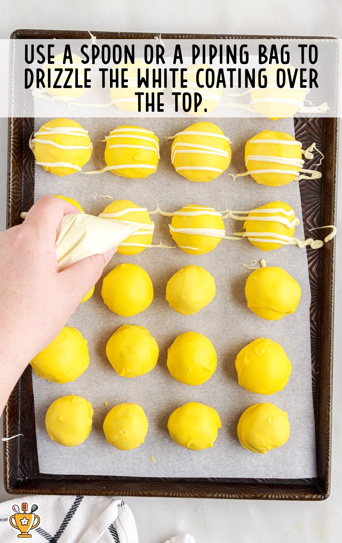 a hand with a piping bag drizzling the white coating over the top