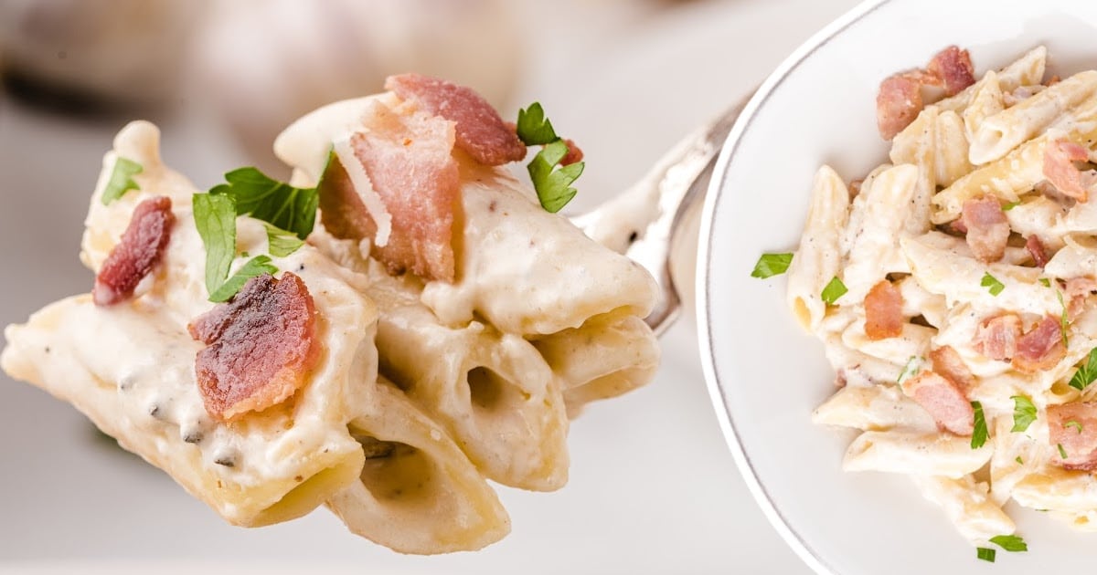 a fork holding some Bacon Pasta and some on a plate