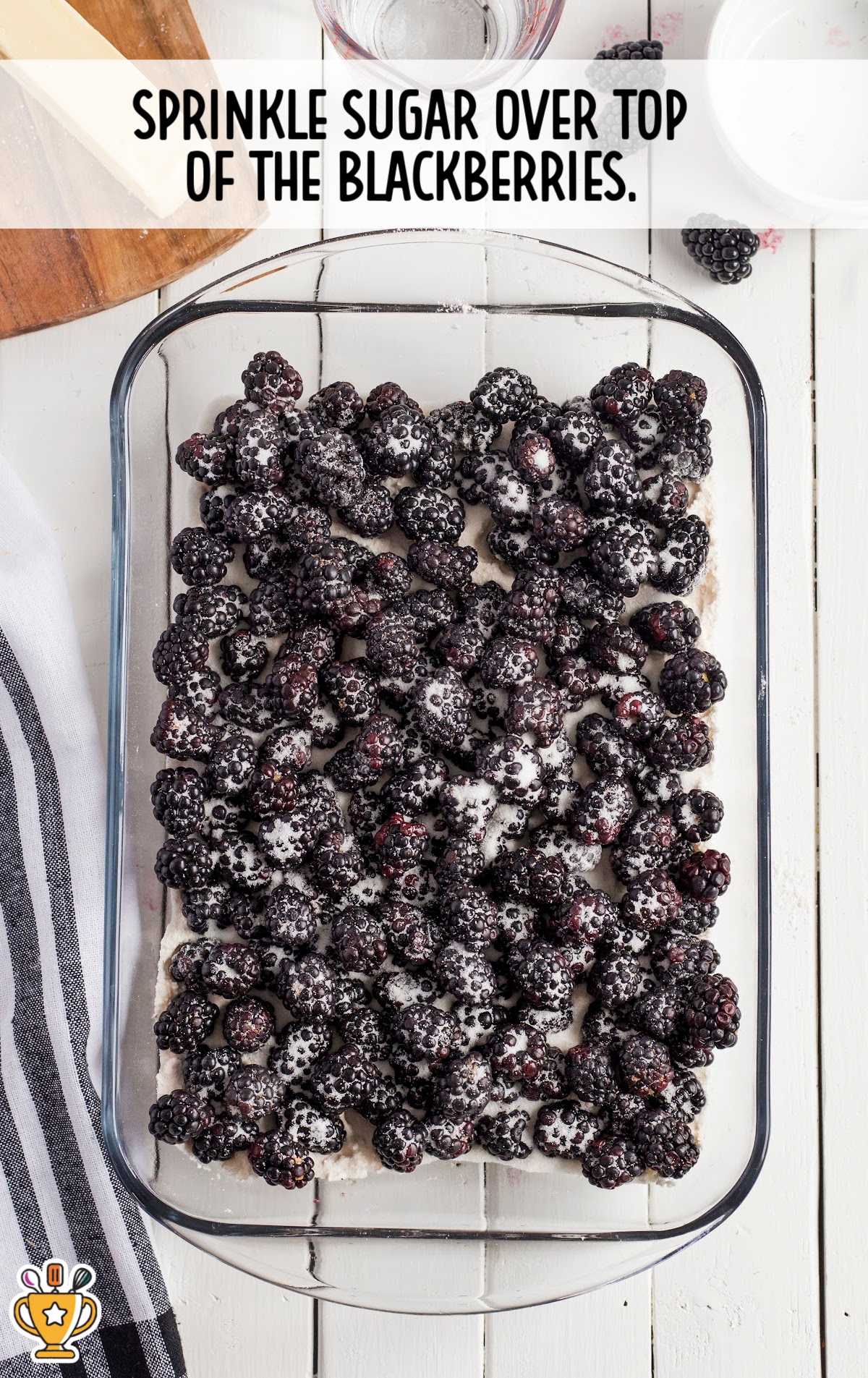 Granulated sugar sprinkled over fresh blackberries in baking dish